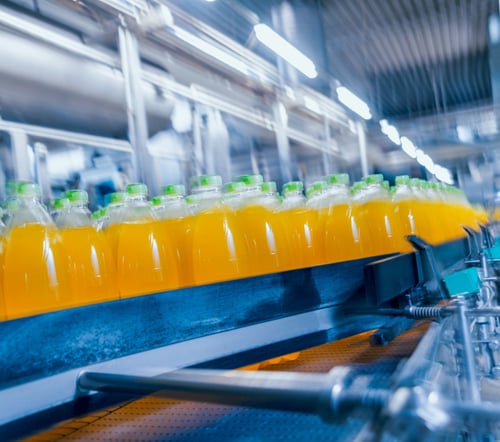 Beverage assembly line with bottles of orange juice