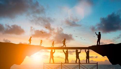 People on scaffolding holding bridge up so others can cross.