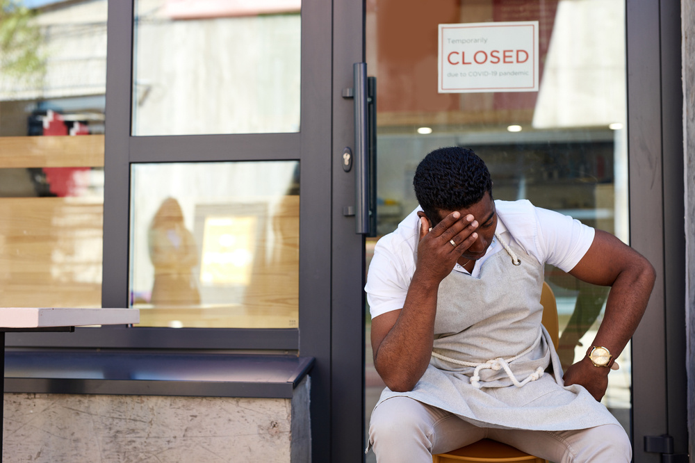 Frustrated business owner sitting in front of his closed business