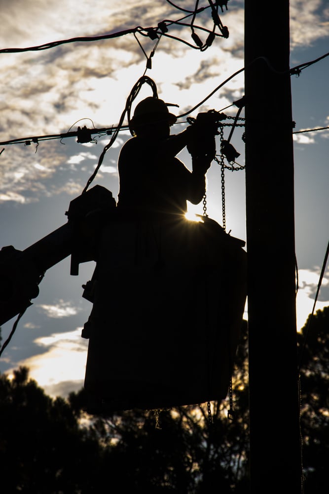 Lineman restores power to neighborhood after storm damages overhead lines.