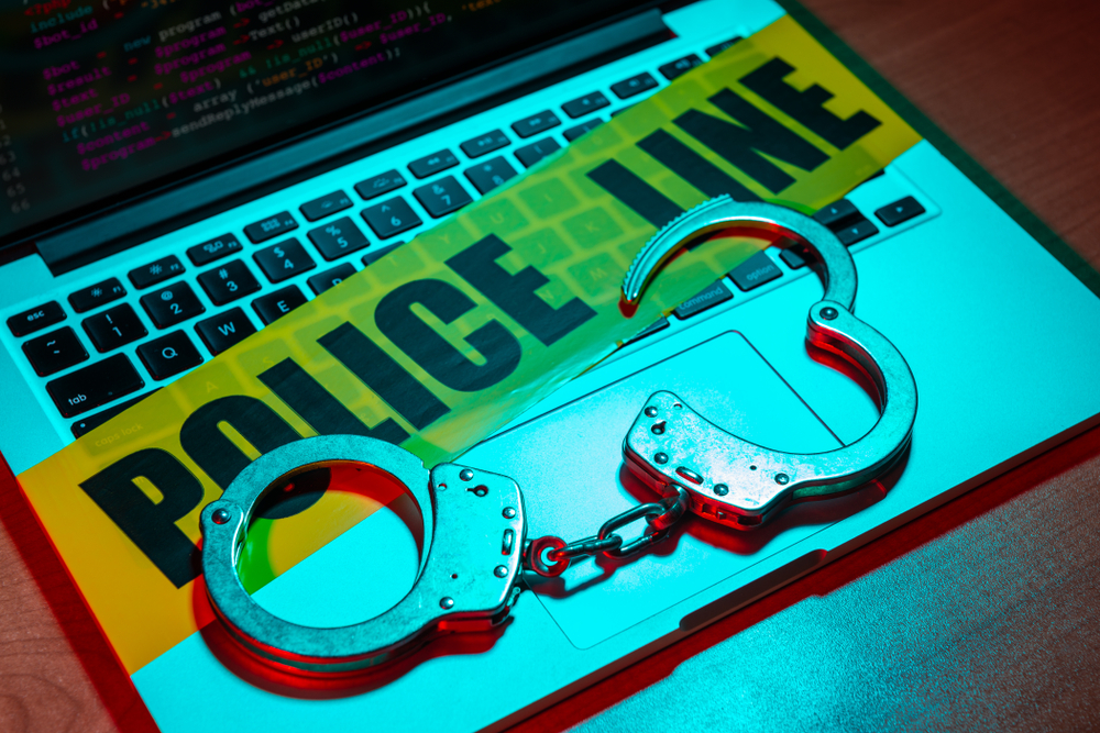 Handcuffs and yellow crime scene tape on a laptop computer