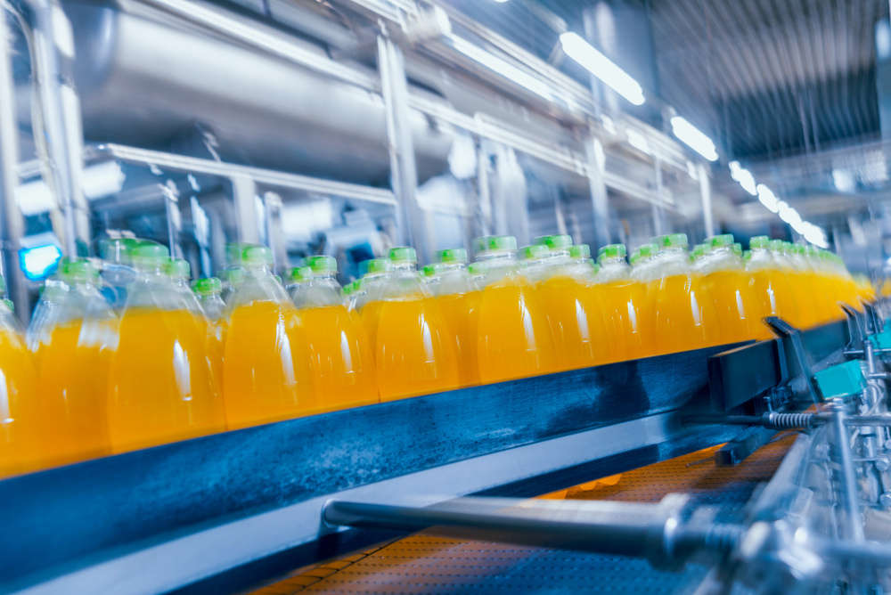 Manufacturing line of orange-colored drinks in plastic bottle