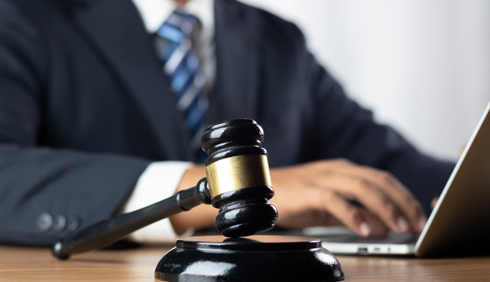 Businessman typing on laptop with gavel in the foreground