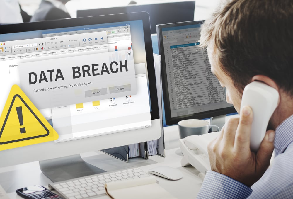 Person on phone in front of computer screen with data breach notification